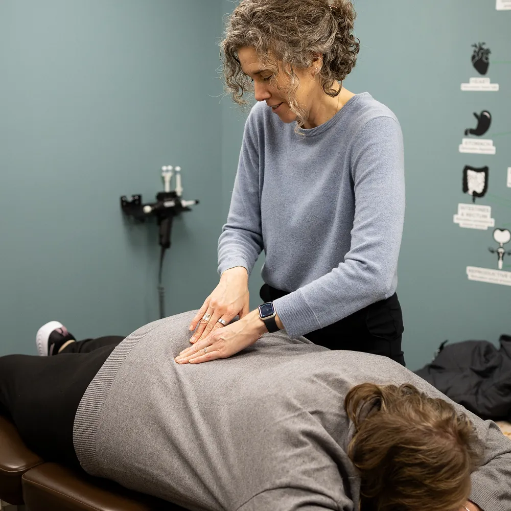 Dr. Stacy LeQuire assessing a patient's lower back at Vitality Chiropractic